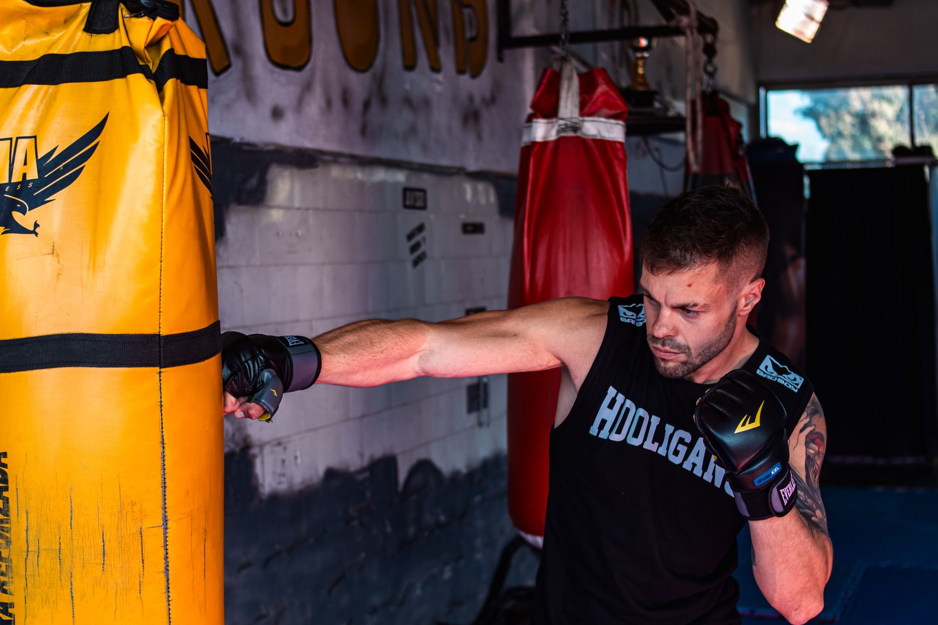 Personal training Strijp-S: Man die boksballen op een zware bokszak slaat in de sportschool