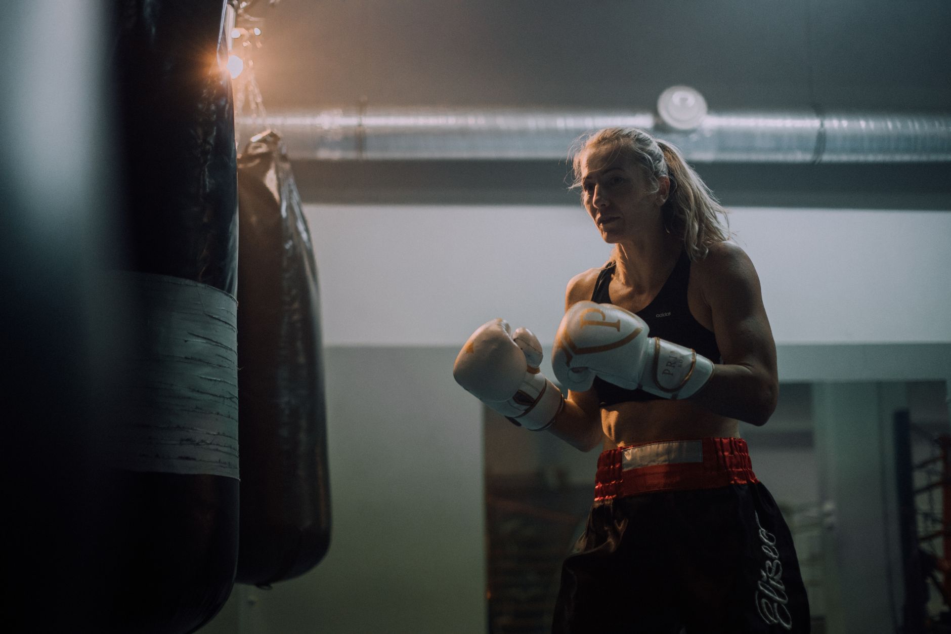 Vastberaden vrouwelijke bokser in een sportschool die oefent met bokshandschoenen en een punchingbal